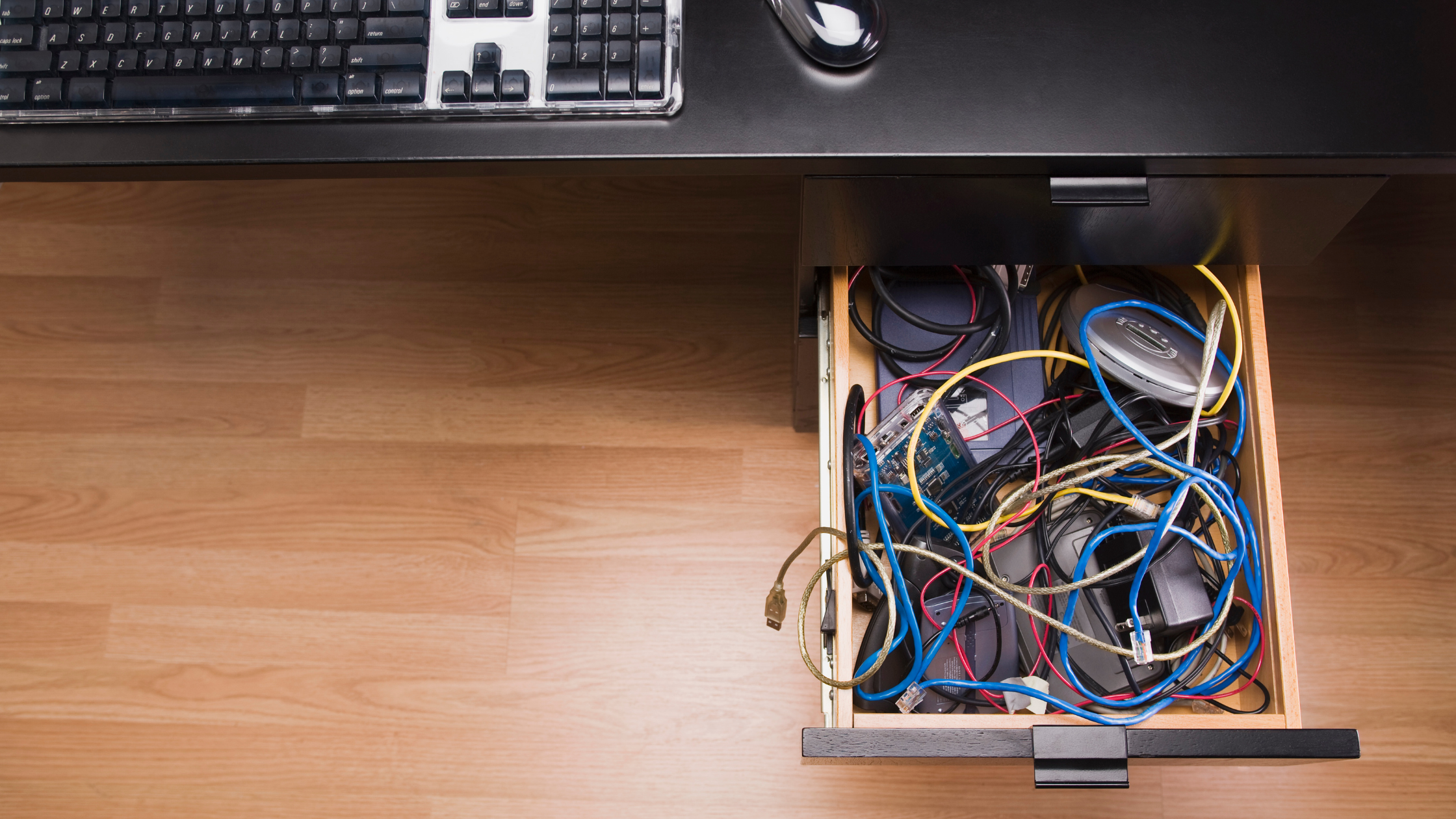 A desk drawer organizer with chargers and cables, each in its own compartment