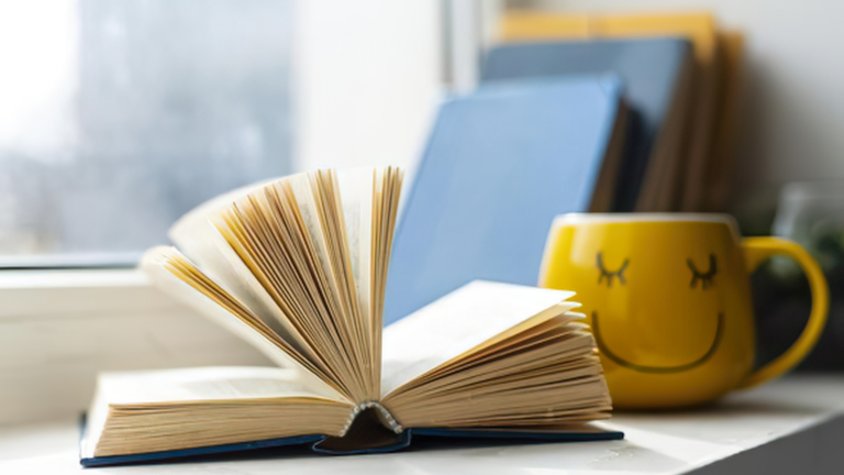 A small book beside a morning coffee — the kind of book to get out of a reading slump.